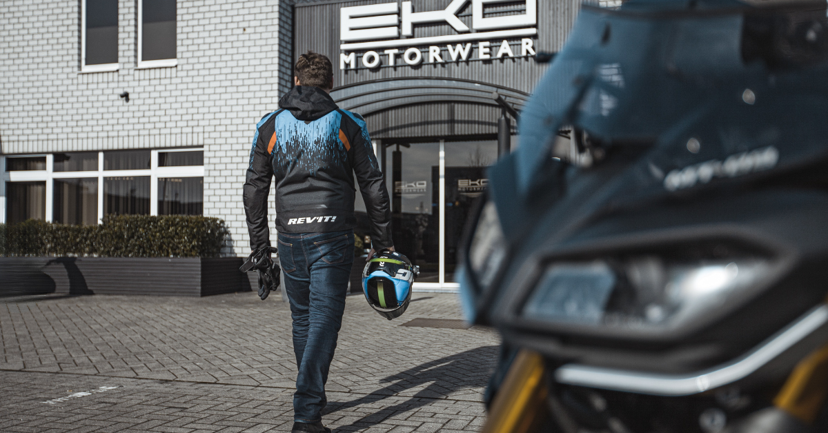 Een motorrijder die af zijn motor stapt en binnenstapt in de motorkledingwinkel EKO Motorwear te Kontich