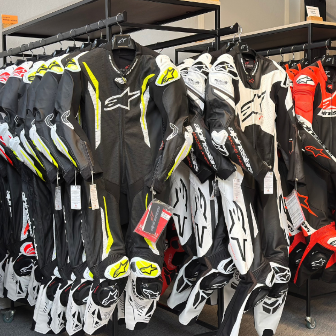 Rek met lederen race motorpakken van Rev'it en Alpinestars